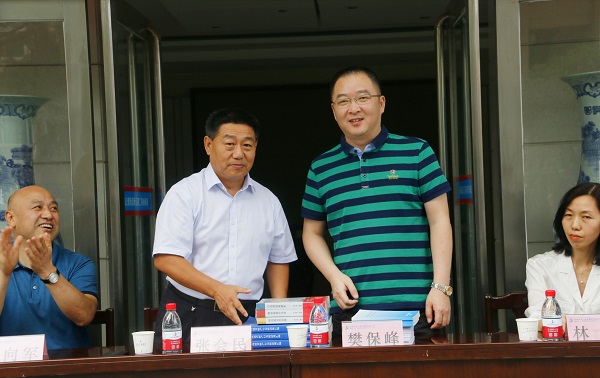 新乡市牧野区税务局党委书记、局长樊保峰向压球(中国)党委书记张会民赠送税法知识书籍.jpg